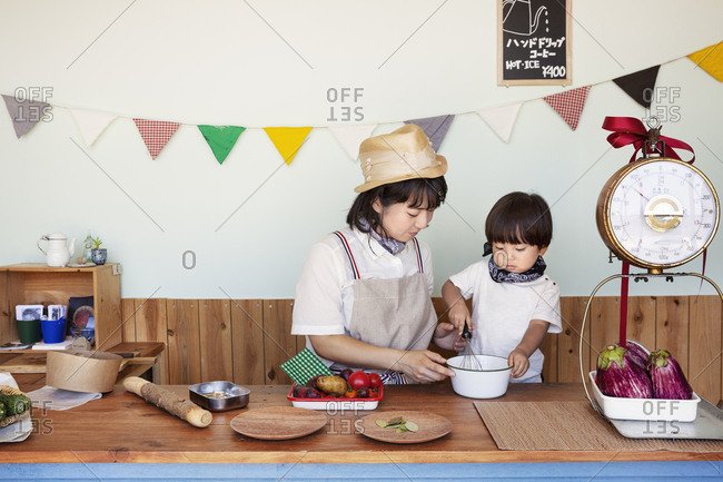 Japanese woman and boy standing in a farm shop, preparing food.
