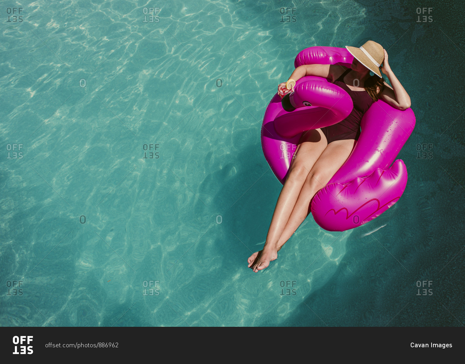 Top view of woman floating on inflatable pink flamingo in a pool.