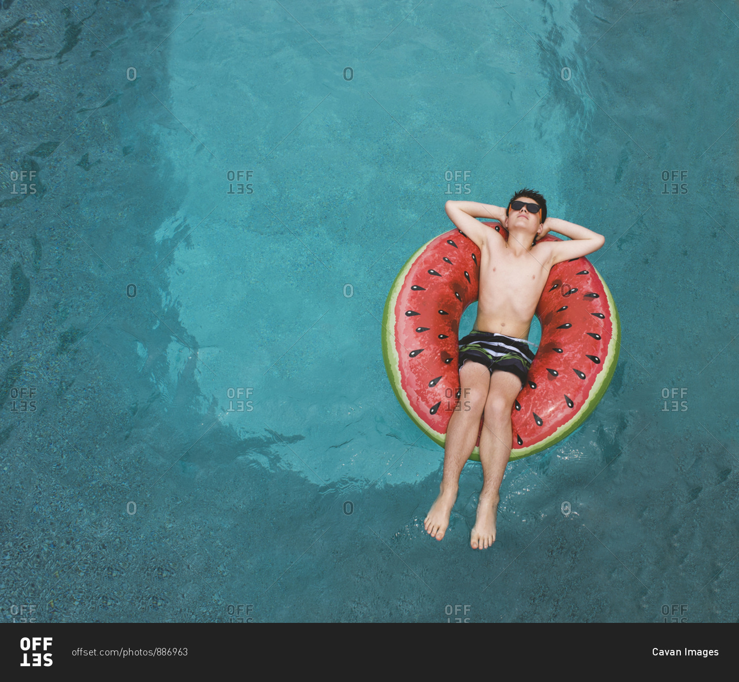 Top view of boy floating on inflatable watermelon float in a pool ...