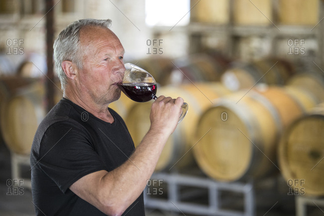 Winemaker (sommelier) sampling his product in a wine storehouse.