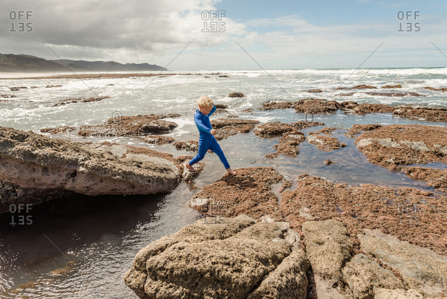 Boy stepping on rocks on the coast of New Zealand
