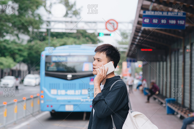 Man is talking on his smartphone while waiting for a tram in Ho Chi Minh city