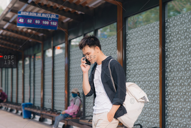 Man is talking on his smartphone while waiting for a tram in Ho Chi Minh city