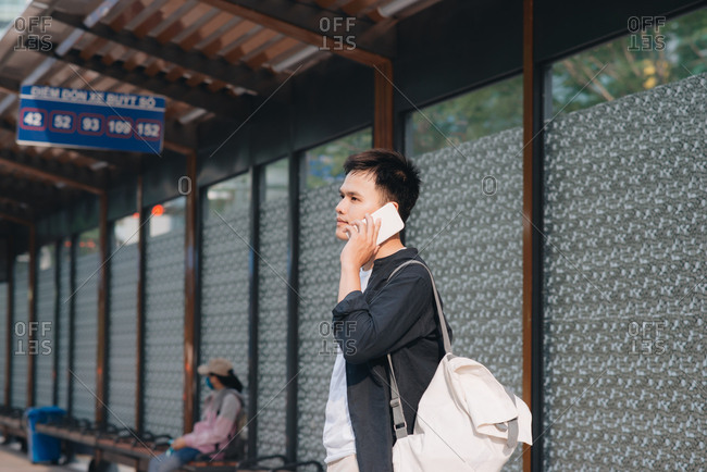 Man is talking on his smartphone while waiting for a tram in Ho Chi Minh city