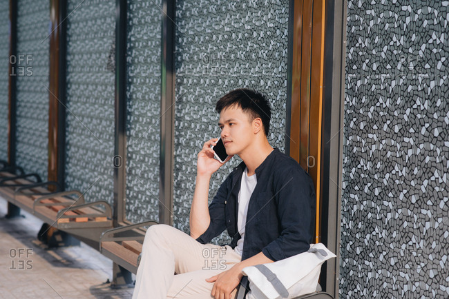 Man waiting at the bus station and talking on the mobile phone