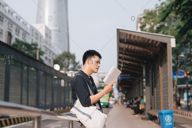Asian tourist man backpacker waiting for bus in Ho Chi Minh city