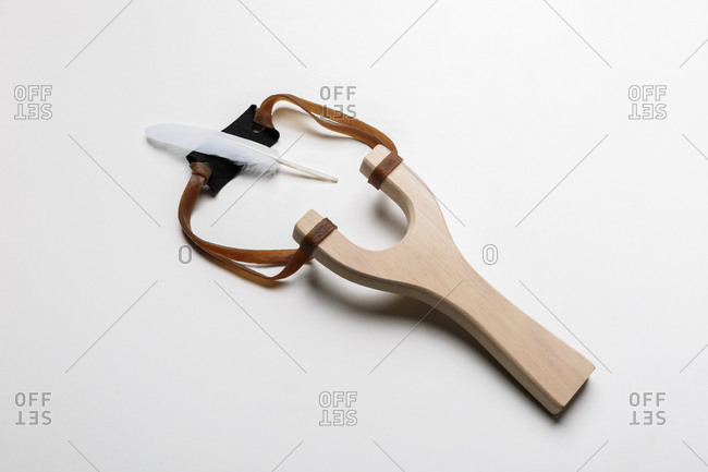 Wooden slingshot with a white feather