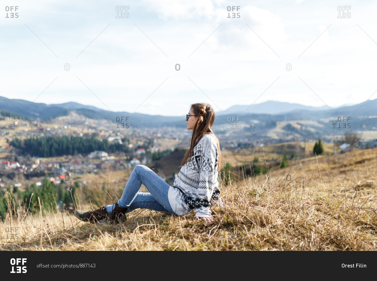 The young woman in the cozy sweater is enjoying the landscape from the foggy mountain
