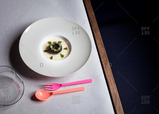 Gourmet dish on table beside pink plastic silverware