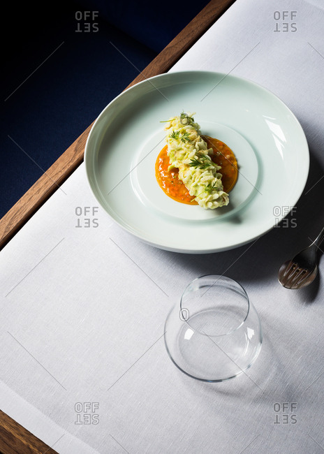 Gourmet dish on table beside empty glass