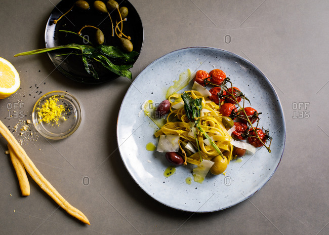 Overhead view of fresh cooked pasta with olives, capers and tomatoes
