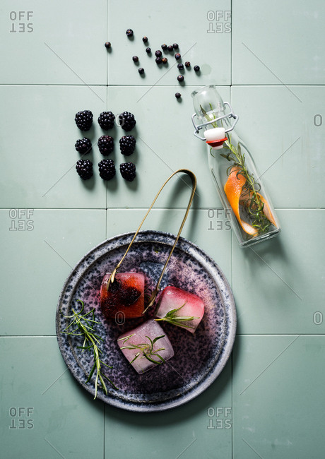 Fruit infused ice cubes on blue tile background