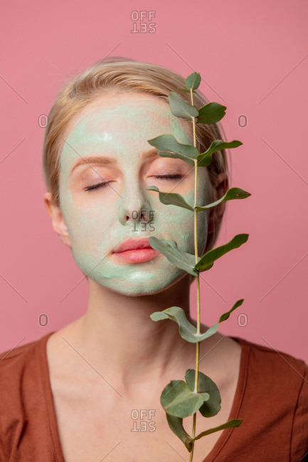 beautiful blond girl with green mask and eucalyptus branch