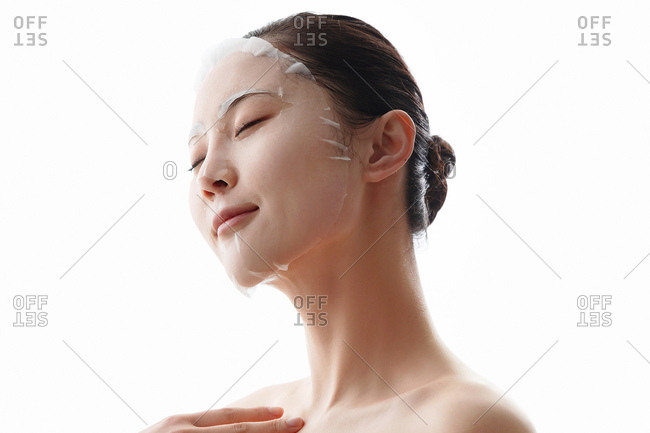 Young woman applies a facial mask