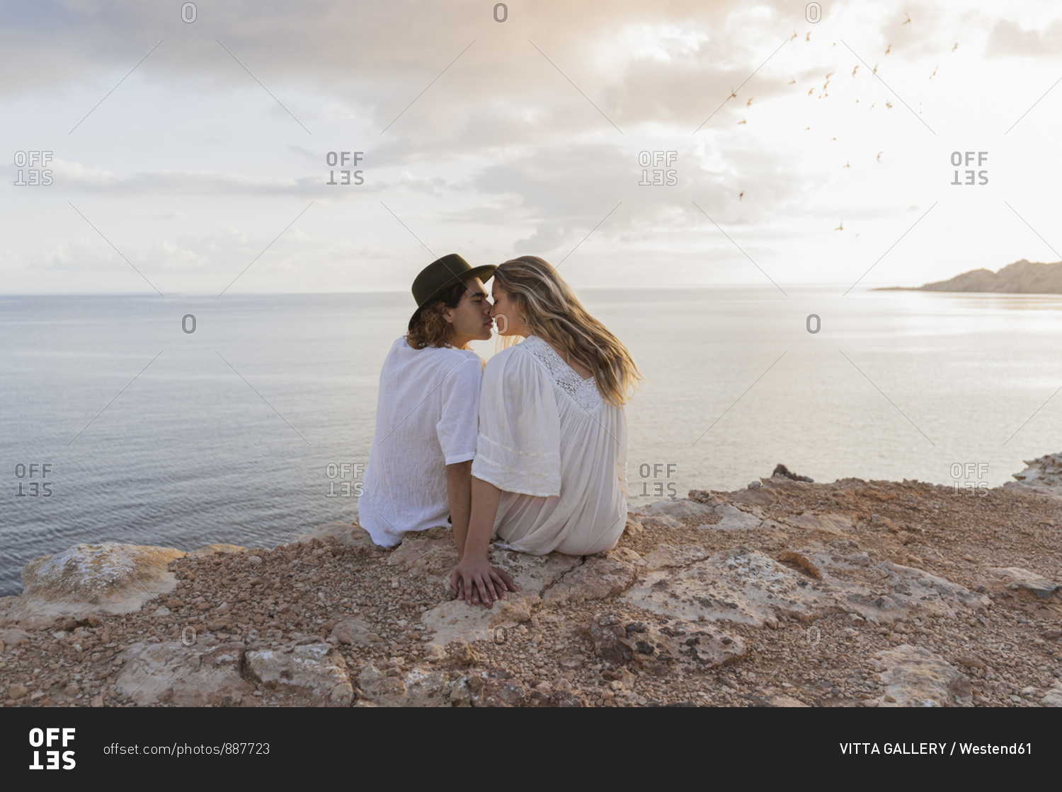 Back view of young couple in love sitting on rock in front of the sea- Ibiza- Balearic Islands- Spain