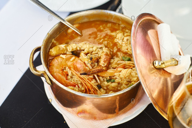 Saffron rice with seafood in a copper pot. Restaurant food for two people. Top view. Portuguese cuisine