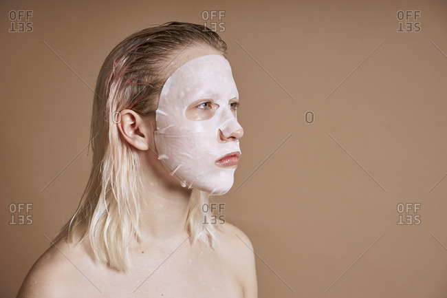 Side view of young and cute woman using beauty face mask