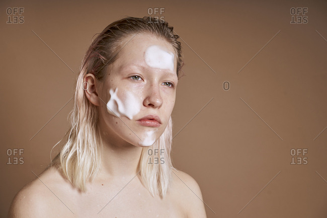 Young woman with cleansing foam on her face