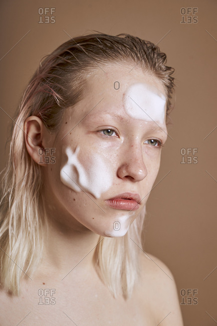 Young woman with cleansing foam on her face