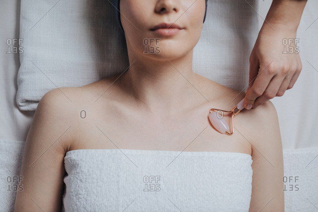 Unrecognizable cropped woman having relaxing massage with crystal roller.