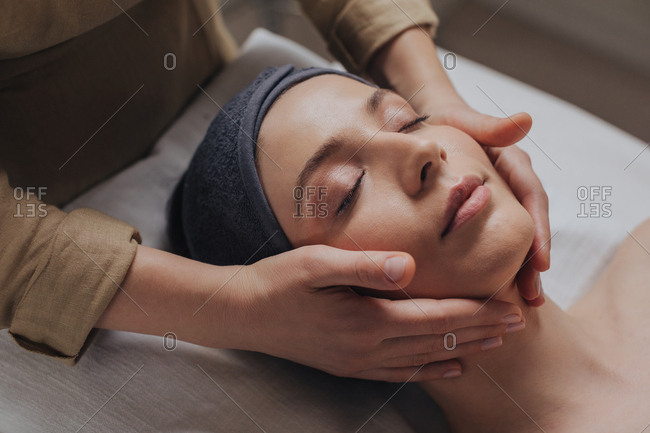 Pretty Caucasian woman enjoying face massage at beauty salon.
