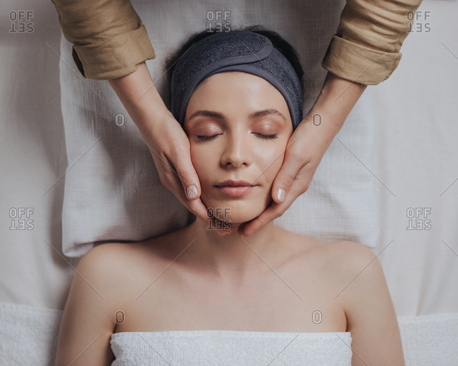 Pretty Caucasian woman enjoying face massage at beauty salon.