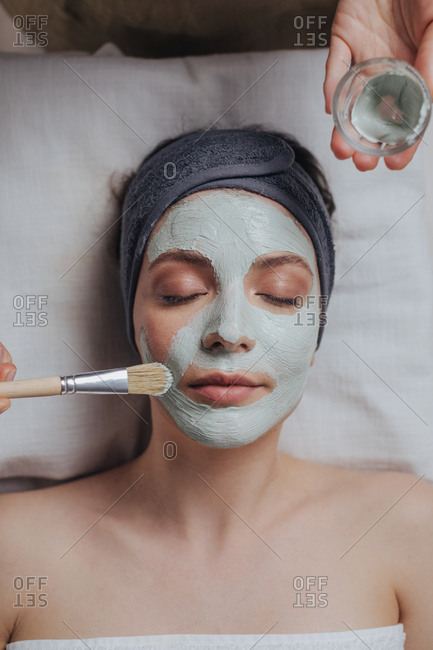 Pretty woman enjoying beauty mask treatment at spa salon.