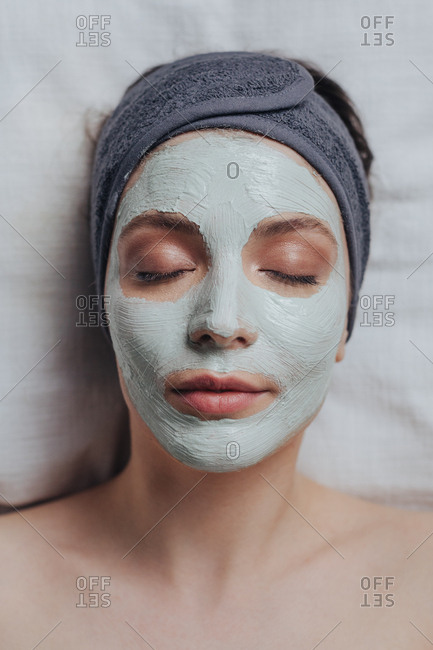 Portrait of pretty Caucasian woman laying at spa salon with cosmetic mask on her face.