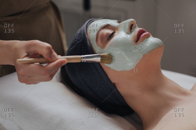 Portrait of pretty Caucasian woman enjoying beauty mast face treatment at spa salon.