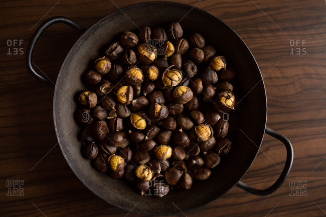 Chestnuts in a wok on a wooden surface