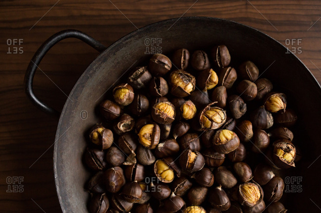 Overhead view of chestnuts in a wok on a wooden surface