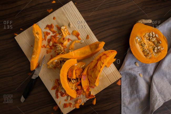 Winter squash being cut on a wooden cutting board