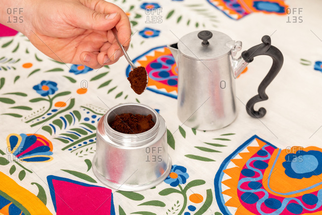Hand filling a moka pot with coffee grounds