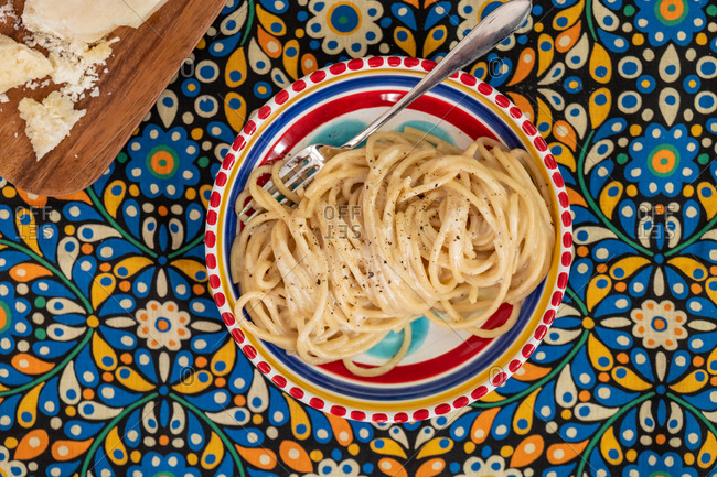Overhead view of cacio e pepe pasta in a dish on a floral background