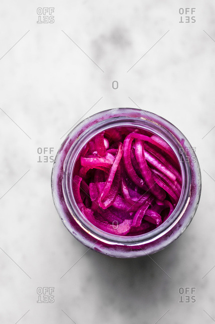 Pickled Red Onions in a jar on a marble surface