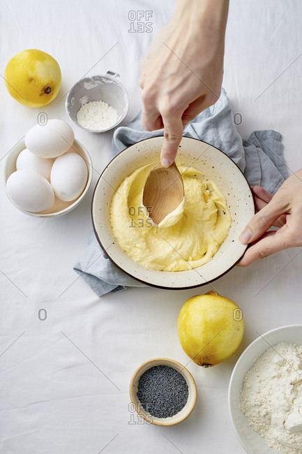 Female hands mixing butter and sugar with wooden spoon while cooking lemon cake