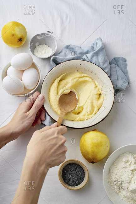 Female hands mixing butter and sugar with wooden spoon while cooking lemon cake