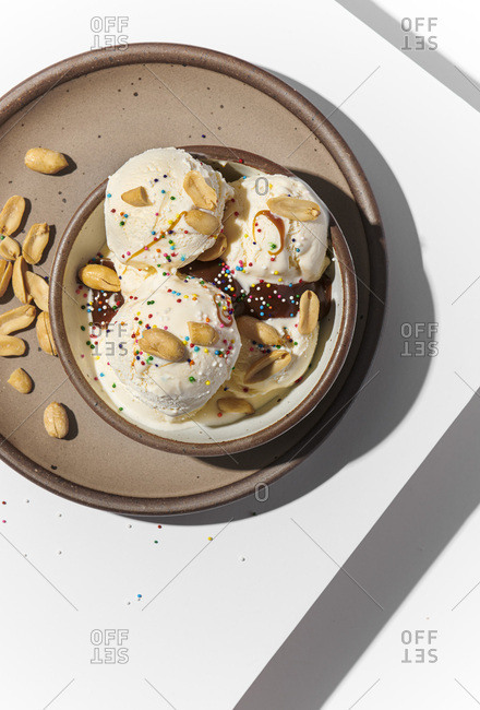 Overhead image of ice cream with toppings. White surface with a lot of contrast and hard shadows, bright lighting.