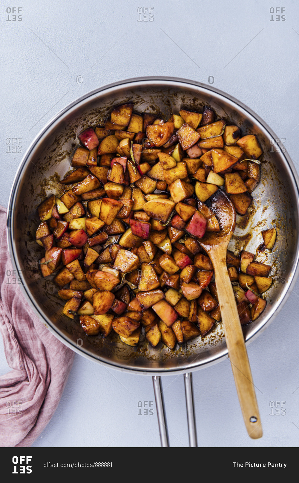 Cooking spiced diced apples with butter and brown sugar in a pan.