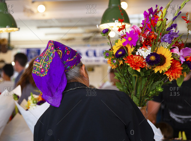 Seattle, Washington, USA - August 3, 2015: Lady flower seller preparing bouquets of flowers at the Pike street market