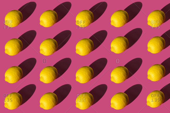 Composition of lemons with hard shadows on a pink background