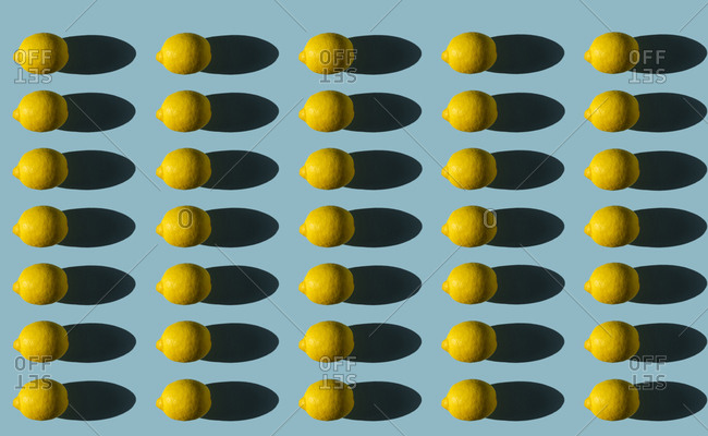 Composition of lemons with hard shadows on a blue background