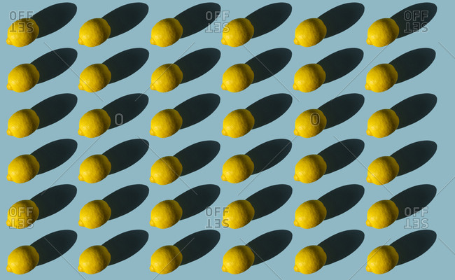 Composition of lemons with hard shadows on a blue background