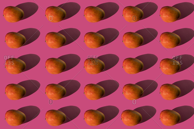 Composition of mangoes with hard shadows on a pink background