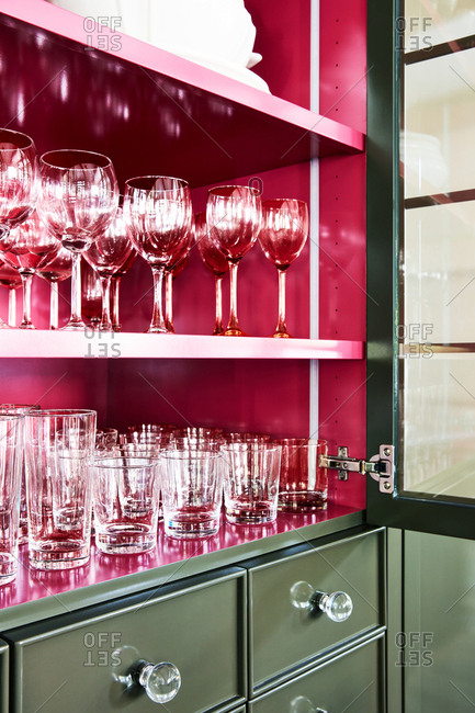 Glassware neatly arranged in a green and red cabinet in a home in Provo, Utah