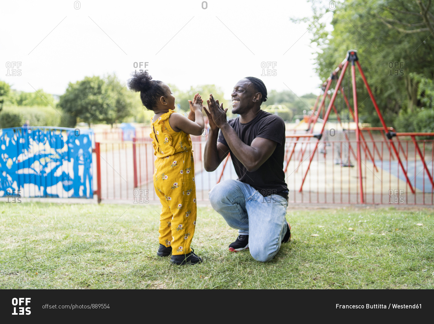 Happy father and daughter playing a clapping game in a park