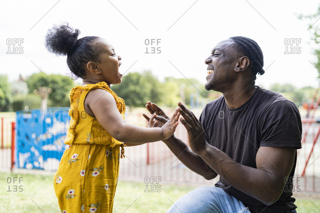 Happy father and daughter playing a clapping game in a park