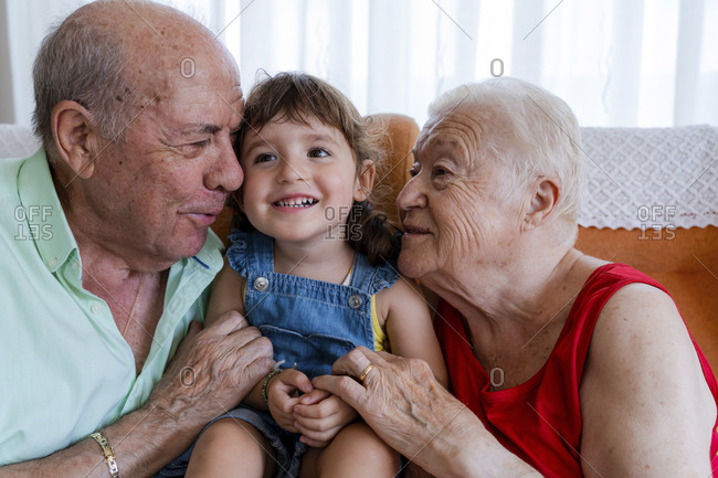 Happy grandparents with little girl at home