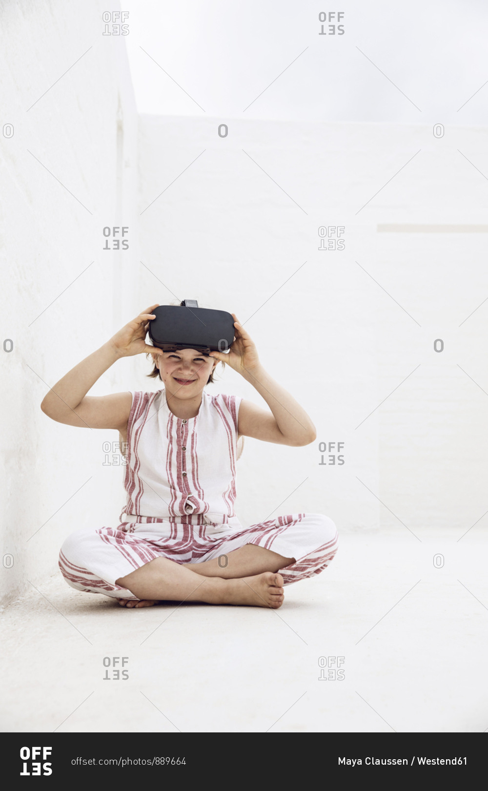 Girl with VR goggles sitting on ground of empty space