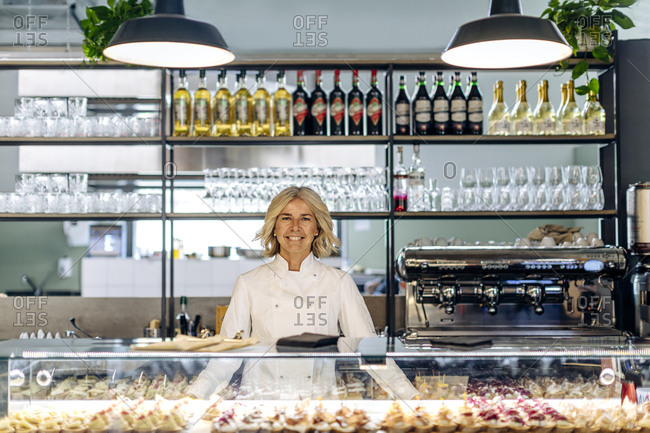Proud bistro owner standing behind pastry counter